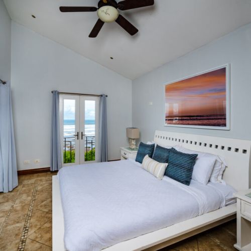 Master bedroom with a king-size bed on the second floor, balcony with jacuzzi, and ocean view.