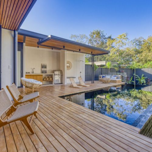 Outdoor spaces are perfectly designed ot relax with a wood deck, infinity pool and green areas.