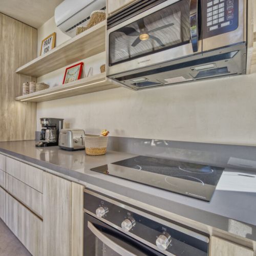 Fully equipped modern style kitchen with induction stove, oven and microwave.